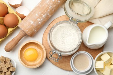 Rolling pin and different ingredients on white table, flat lay