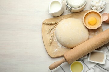 Rolling pin and different ingredients on light wooden table, flat lay. Space for text
