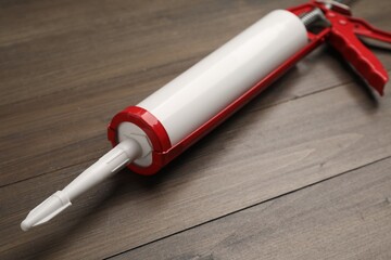 One glue gun on wooden background, closeup. Construction tool