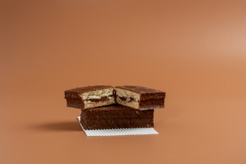 A delicious chocolate cake is cut in half and placed on white paper against a brown background. The...