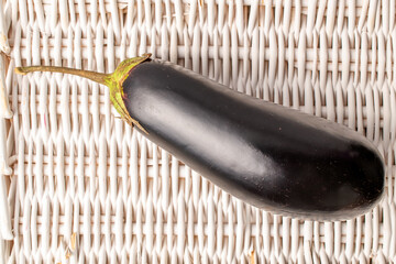 One dark purple eggplant, close-up, on a vine tray, top view.