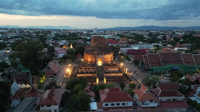 Wat Chedi Luang Temple in Chiang Mai old city at dusk lit up with lights. Aerial 4K drone footage of UNESCO heritage Bhuddist temple in Chiang Mai, Thailand.