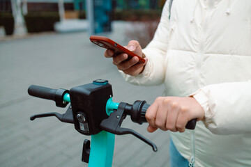 Handsome man using smartphone app. Guy approaches an electric scooter and using mobile phone app NFC contactless locker on bike bicycle in sharing parking lot. High quality photo