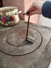 A close-up of a metal fireplace poker resting on a stove, symbolizing traditional heating, fire...