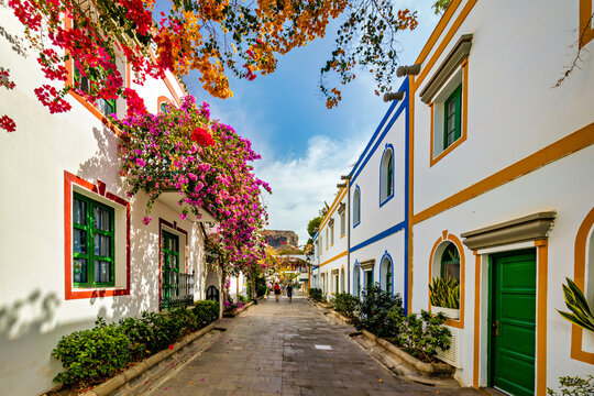 Street with blooming flowers in Puerto de Mogan, Gran Canaria, Spain. Favorite vacation place for tourists and locals on island. Puerto de Mogan with lots of bougainvillea flowers, Canary Island.