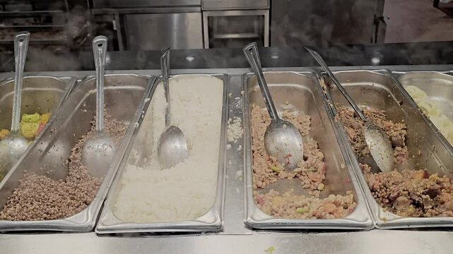 A row of silver trays with spoons in them. The spoons are in different sizes and are in different trays