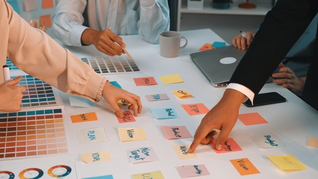 A vibrant workspace showcasing a team engaged in a brainstorming session. Colorful sticky notes and swatches reflect creative planning and collaboration efforts. SACTR
