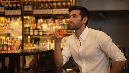 Smart man in white shirt drinking cocktail Old fashioned waiting friends or couple while chatting on smartphone in special party beverage vibrant at nightclub on Friday meeting night time. Vinosity.