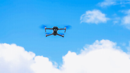 Drone with a camera flies against the background of trees and sky