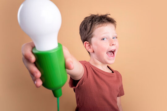 Child Holding Light Bulb Smiling with Brilliance and Joy