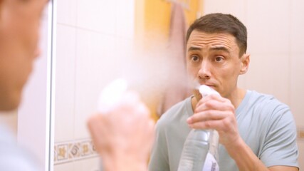 Fototapeta premium Man cleaning bathroom mirror with spray bottle