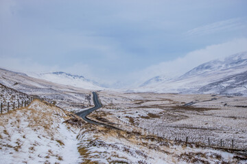 Obraz premium Winding road in a Snowy Scottish Mountain Valley