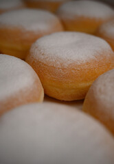 Close-up of golden donuts with sugar powder. Perfect texture and soft dough. Ideal for bakery promotions, coffee shop branding, and dessert advertising.