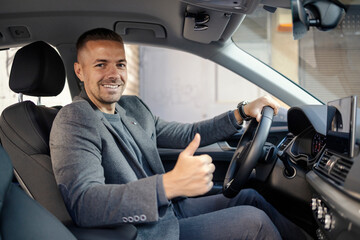 Happy elegant business casual driver is giving thumbs up while driving his classy car.