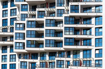 Modern architecture of a tall condo building in the city. Concrete exterior with glass balcony,...