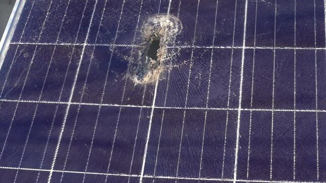 Solar panel with hole and crack on a bright sunny day.