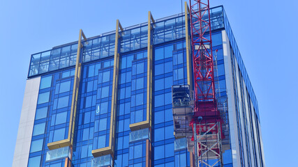 Fototapeta premium Crane on the construction site in a site surrounded by the high buildings.