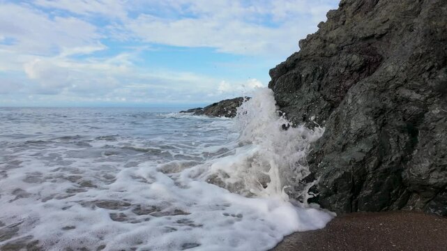 Ocean waves crash into a rock in slow motion