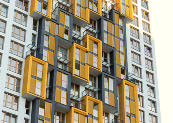 Fototapeta premium Modern high-rise residential building with bright yellow balconies in an urban metropolis.