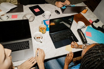 High angle view male and female business professionals with laptops discussing in meeting at office