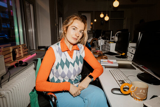 Portrait of redhead female entrepreneur sitting on chair at desk in office