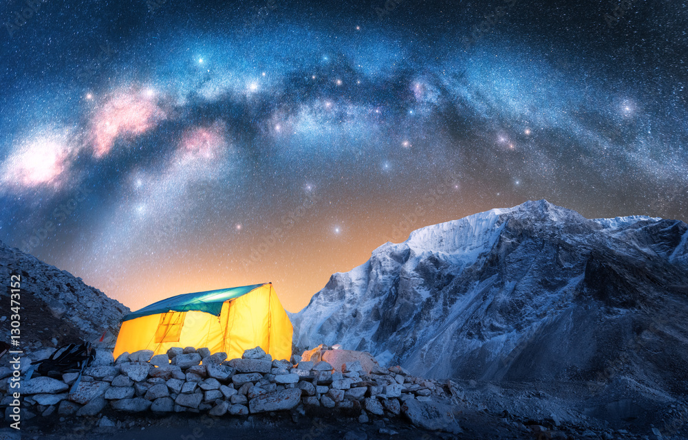 Wall mural milky way acrh over glowing yellow tent in the snowy mountains at starry night. hiking and trekking 