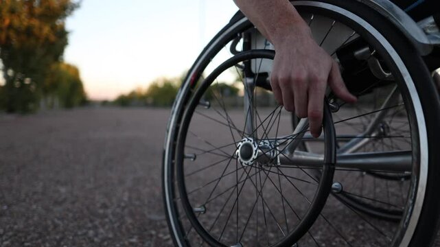 Athlete using handbike wheel on wheelchair in park during sunset