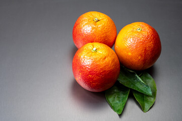 Sicilian sweet juicy yellow and red blood oranges with green leaves close-up