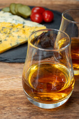 Whiskey and cheese pairing, tasting whisky glasses and plate with sliced crumbly old blue stilton and blue shropshire cheeses, Great Britain food and drink