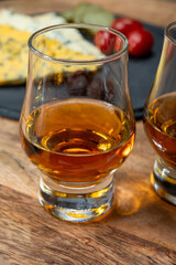 Whiskey and cheese pairing, tasting whisky glasses and plate with sliced crumbly old blue stilton and blue shropshire cheeses, Great Britain food and drink