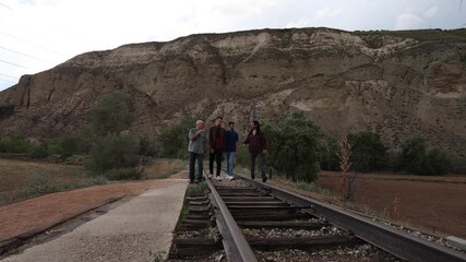 Musicians walking on railroad tracks in scenic landscape
