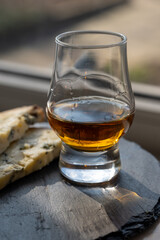 Whiskey and cheese pairing, tasting whisky glass and plate with sliced blue stilton and blue shropshire cheeses, Great Britain food and drink