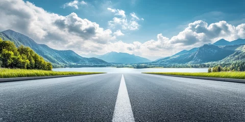 Fototapeten Empty asphalt road with a blue sky and white cloud background, a lake, and a mountain landscape view. Beautiful scenic panorama of natur © El Media