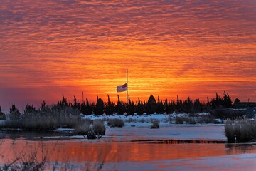 CLoudy sunrise behind half mast flag