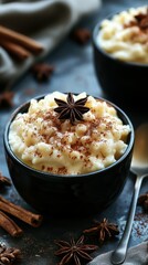 Creamy rice pudding topped with spices and star anise in dark bowls on a rustic table