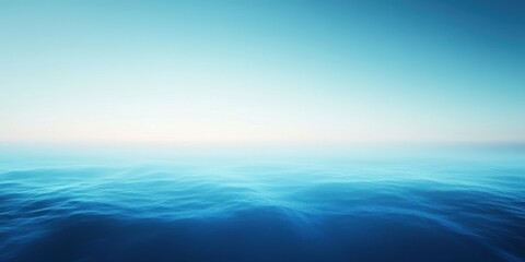 Obraz premium Vast blue ocean under a clear sky at dusk, calm water stretches toward the horizon with gentle waves and soft light
