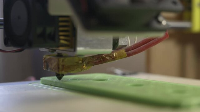 Poorly calibrated 3d printer struggling to print a large flat object in green pla filament.  3d printing defects and errors concept.