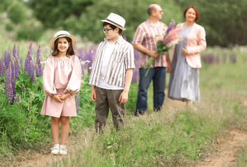 Fototapeta premium Happy caucasian family enjoying nature walk with lush flowers in blooming meadow