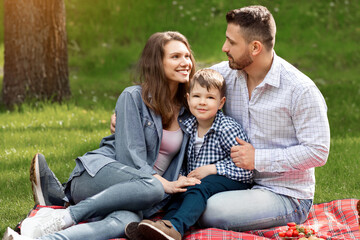 Fototapeta premium Loving family with adorable child spending weekend together on picnic at park