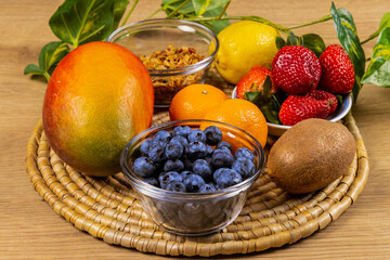 mango, kiwi, strawberry, oranges, and blueberry fruit for salad on a woven place mat