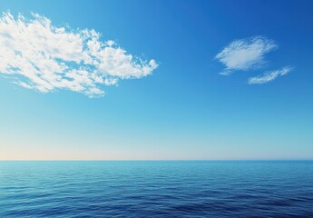 Obraz premium Serene Coastal Landscape with Clear Blue Sky and Tranquil Ocean Waves Under Soft White Clouds in a Calm Horizon View