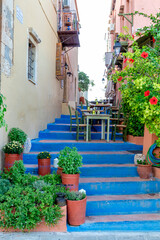 Obraz premium A bright blue staircase decorated with potted plants and a charming c charming restaurant awaits you in the quaint village. Greece. Rethymno.