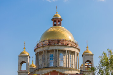 Golden domes of church under construction reflecting blue sky