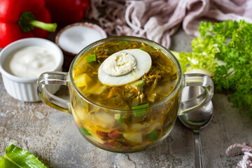 Soup with sorrel and egg in a transparent plate close-up. Hot soup with sorrel for lunch. Close-up
