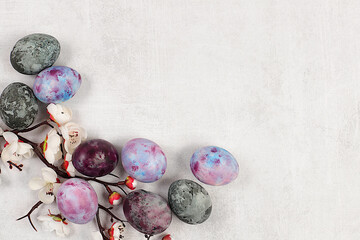 Easter eggs on a light elegant background with sakura branches, ideas for homemade Easter preparations. Marble eggs painted with hibiscus tea, Easter celebration concept