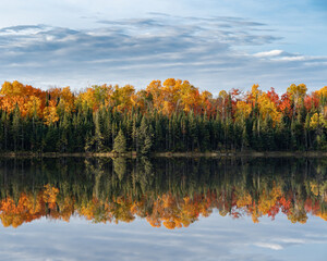 A beautiful fall scene with fall foliage reflected on a glassy lake.