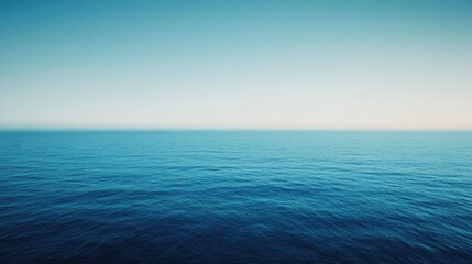 Fototapeta premium Calm and serene ocean view at sunrise with gradients of blue water and clear skies.