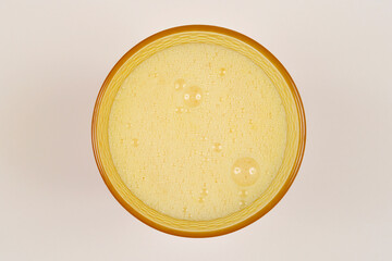 A top-down, close-up view of foamy fresh orange juice in a glass, showcasing the texture and bubbles