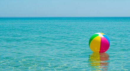 Colorful beach ball floating on clear turquoise water evoking a playful summer vibe at a serene seaside location