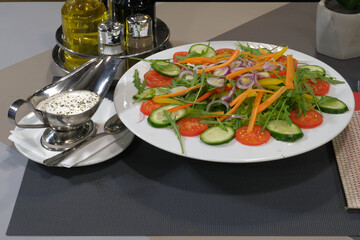 A vibrant salad featuring fresh cucumbers tomatoes carrots peppers and onions accompanied by a creamy dressing Healthy and flavorful